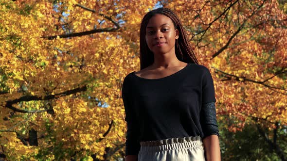 Young Beautiful Black Woman Waves with Hand To Camera in Autumn Park