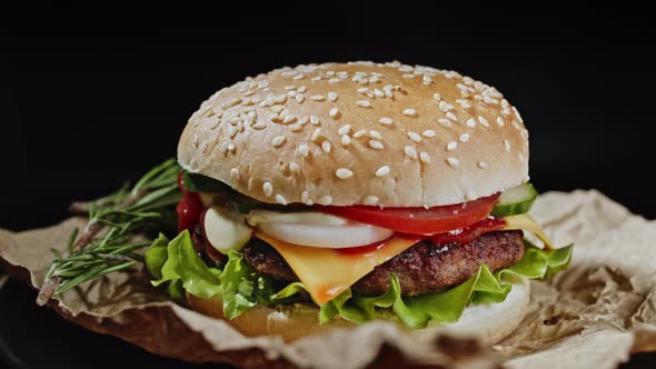 Big Appetizing Burger with Rosemary, Meat Cutlet, Onion, Vegetables, Melted Cheese, Lettuce and