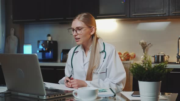 Female Doctor in Medical Gown Making Video Call To Patient From Home