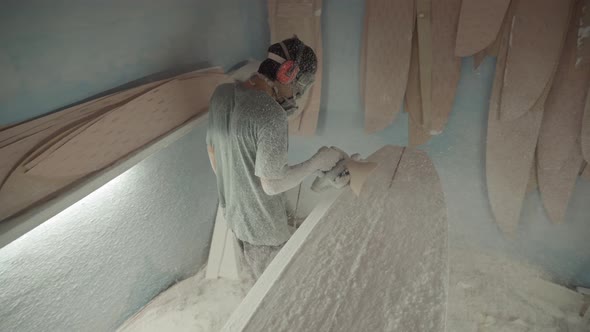 Worker Polishing Surfboard Blank with Automatic Polisher