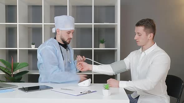 Male Doctor in the Office Measures the Pressure of a Male Patient.