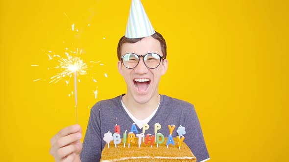 Happy Birthday Concept. Young Funny Man with a Cake o an Orange Background