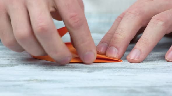 Hands Folding Origami From Orange Paper.