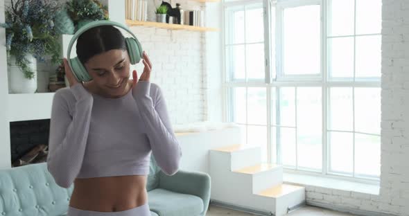 Happy Cheerful Young Woman Dancing Alone at Home and Using Smartphone for Listening Music