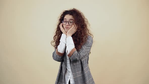 The Sad and Upset Young Woman with Her Hands on Her Cheeks Looks Down