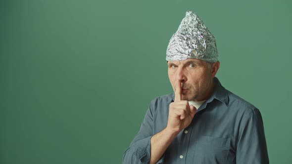 A Paranoid Man in a Protective Foil Hood Warns To Be Quiet