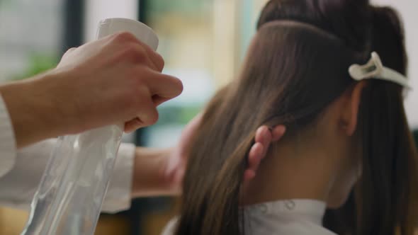 Handheld view of hairdresser spraying the hair with beauty product