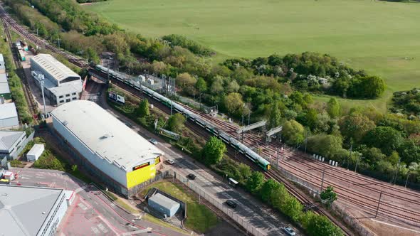 dolly back drone shot following southern railway class 377 train through north west London