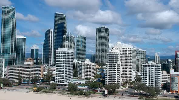 Moving aerial view of a coastal city skyline with cloudy blue sky