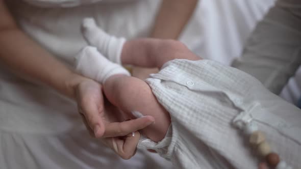Female Hand Applying Moisturizer Rubbing Cream in Leg of Newborn Baby in Slow Motion