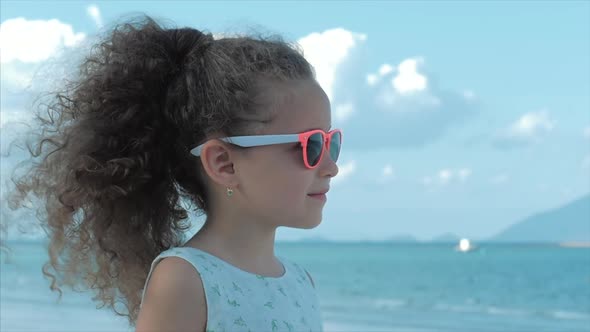 Close-up Portrait of a Beautiful Little Girl in Pink Glasses, Cute Smiling, Looking at the Sea