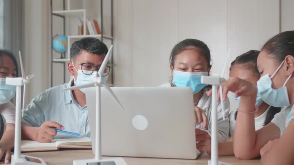 Children Are Wearing Facemasks And Work As A Team Using Laptop Computers To Program Wind Turbines