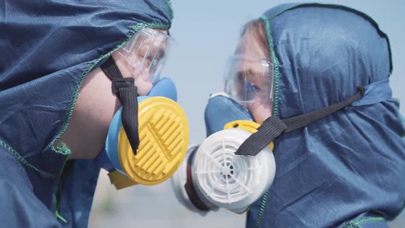 Close-up Faces of Caucasian Man and Woman in Respirators and Protective Eyeglasses. Side View