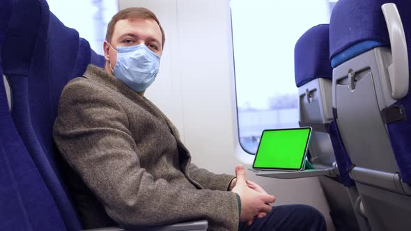 Millennial Man in Medical Mask Rides on Train and Tablet Computer with Chroma Key Green Screen