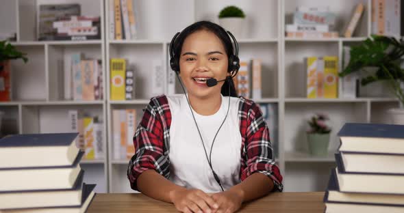 Happy female student in headphones and glasses talking at camera