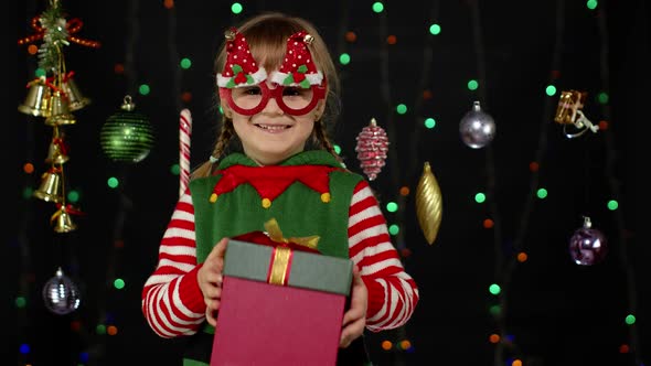 Kid Girl Christmas Elf Santa Helper Giving Present Gift Box To Camera