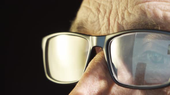 An Elderly Man with Glasses Looks at the Computer Screen