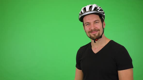 A Young Handsome Cyclist Waves at the Camera with a Smile - Green Screen Studio