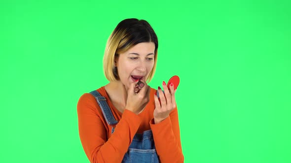 Girl Paints Her Lips Looking in Red Mirror. Green Screen