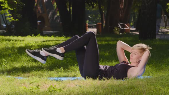 Athletic Slender Strong Caucasian Woman Trainer Female Lady Lies on Mat on Grass Outdoors in Park