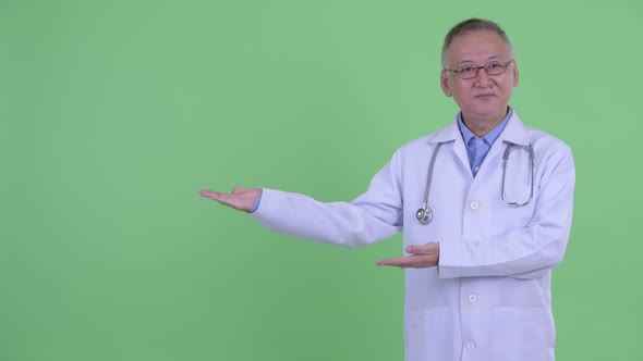 Happy Mature Japanese Man Doctor Showing Something