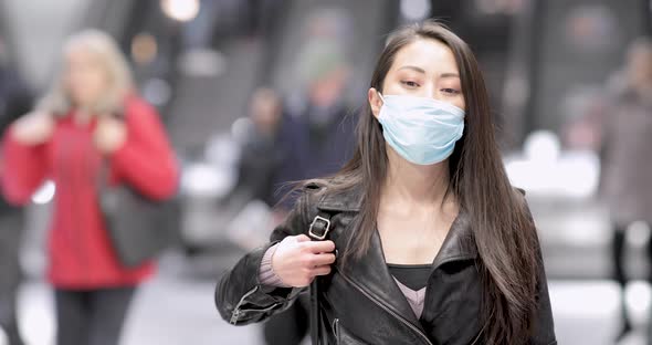 Chinese woman at train station in London wearing face mask to protect from co