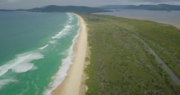 Beautiful aerial flight over beach road along wild blue ocean, Australia