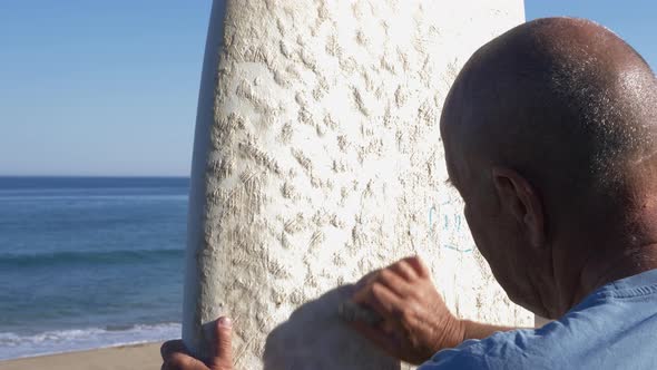 Man waxing surfboard on coast, Lorne, Victoria, Australia