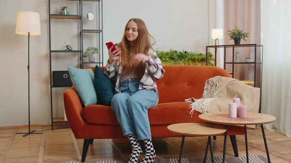 Cheerful Young Woman Sitting on Sofa Using Mobile Phone Share Messages on Social Media Application