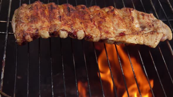 Delicious Spiced Ribs are Frying on the Grill Grid on the Background of the Fire