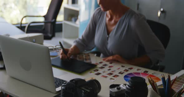 Female graphic designer using graphics tablet at desk 4k