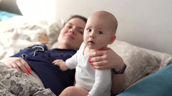 Mother Plays with Her Baby at Home on Her Lap