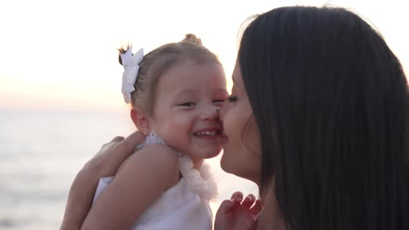 Closeup Happy Mother Kissing Baby Daughter in Sunrays As Girl Smiling Hugging Woman