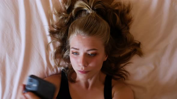 Young woman lying on bed and taking selfie