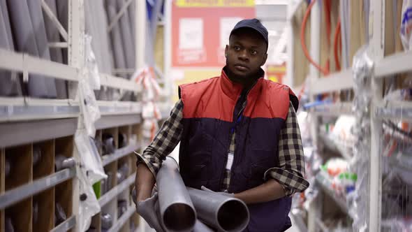 Workman Walks with Water Pipes in Plumbing or Hardware Store