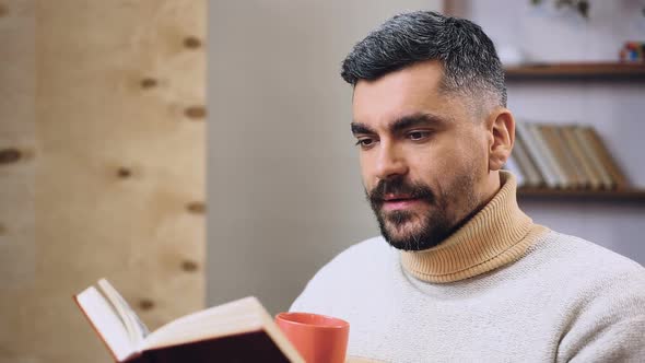 Bearded Man Reading Interesting Book and Drinking Tea or Coffee, Leisure Time