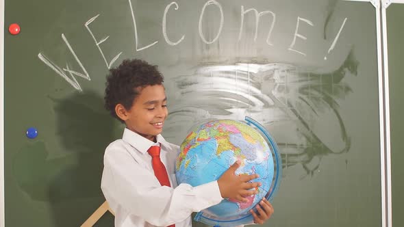 African American Boy with Globe on Study Table on Chalk Board Background