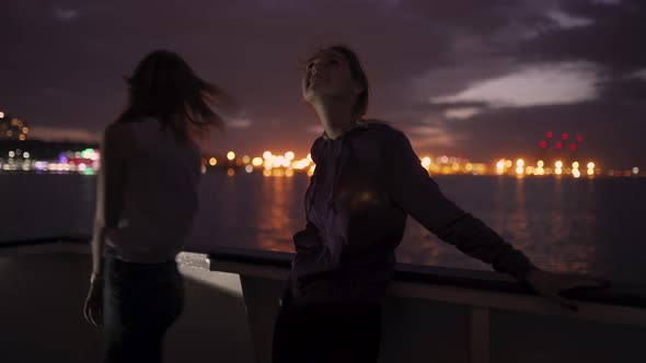 Silhouette of Two Attractive Young Women Traveling on a Ship at Night