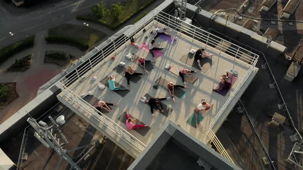 A Group of People Do Yoga on the Roof of a Building on a Sunny Summer Evening