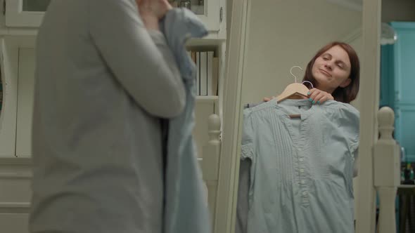 Woman Choosing Dresses to Wear Standing in Front of the Mirror