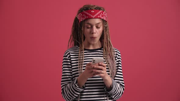 Surprised hippie woman typing on phone