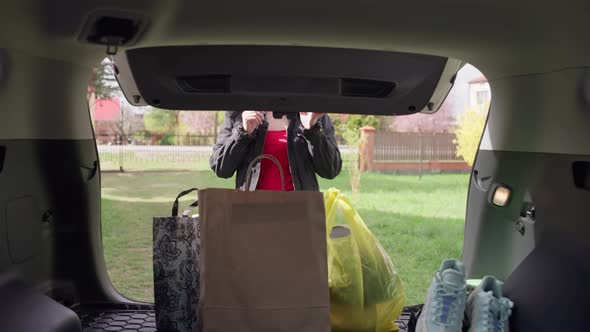 The Girl Picks Up Shopping From the Trunk