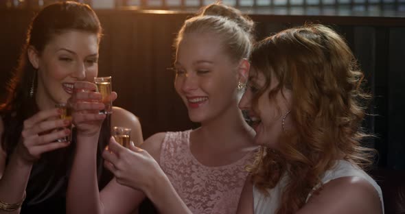 Three female friends toasting shot glasses of tequila