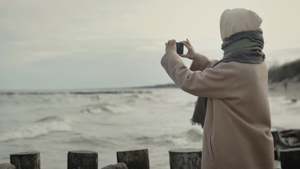 Woman take photo with mobile phone of sea