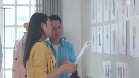 Asian Male And Female Designers Looking At The Picture In Hands And Discussing About Design