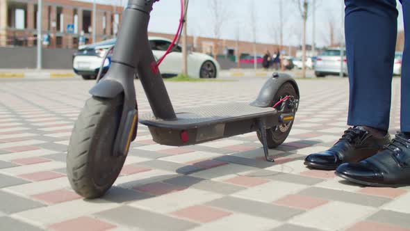 Male Legs in Trendy Black Shoes Stepping on Electric Scooter