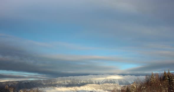 Clouds rolling over the snowy mountain landscape in winter at sunrise