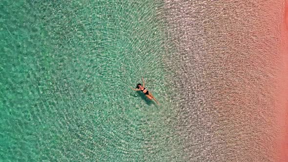 Aerial view of attractive woman at pink beach, Padar islands, Indonesia.