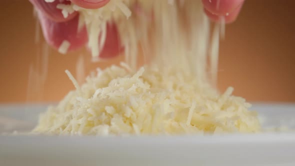 sprinkle grated parmesan cheese close-up. a man takes cheese in his hand and sprinkles it