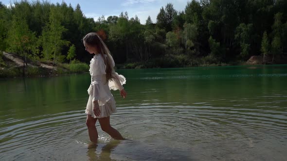 Young Beautiful Woman Is Walking on Shallow of Forest Lake at Summer, Enjoying Good Weather